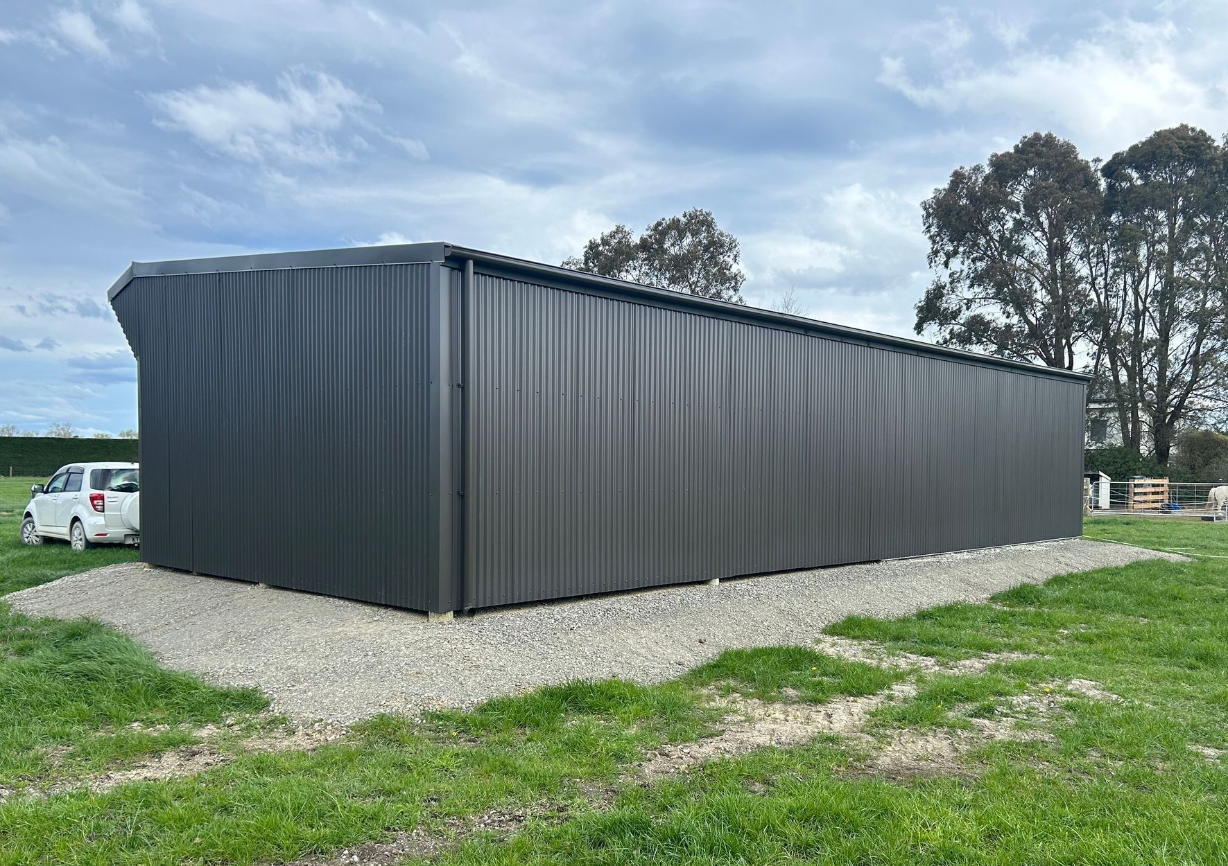 A large black building is sitting in the middle of a grassy field.
