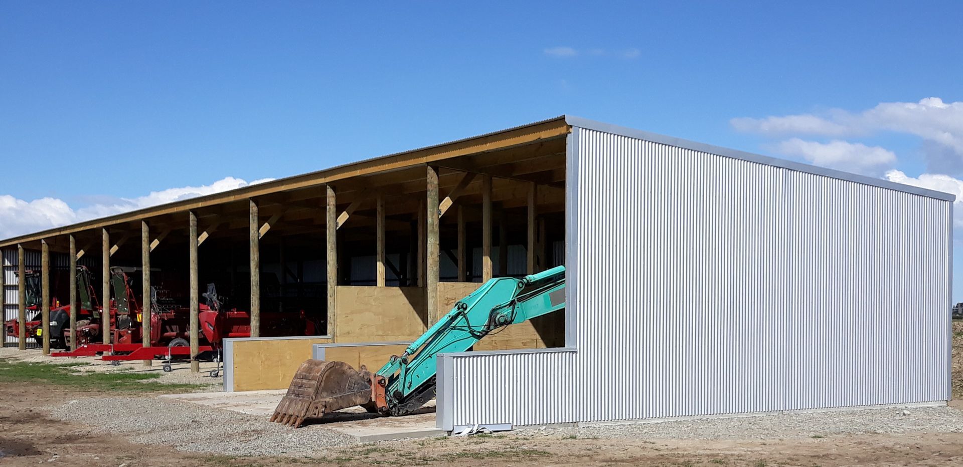 A large white building with a green excavator in front of it.