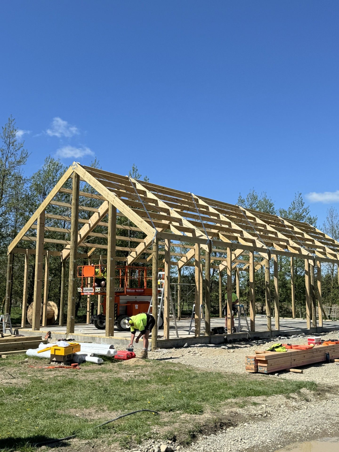 A large wooden structure is being built in the middle of a field.