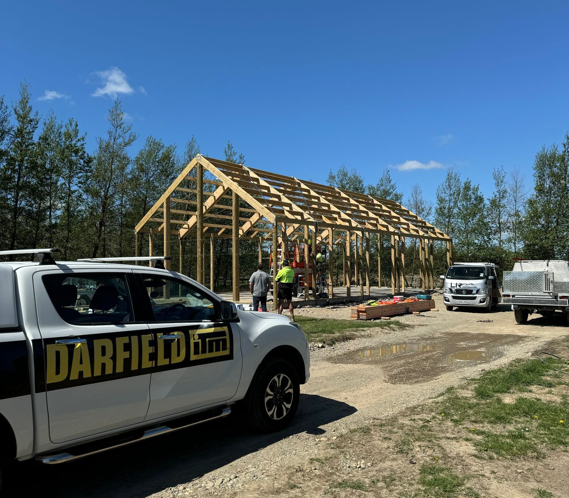 A darfield truck is parked in front of a building under construction.