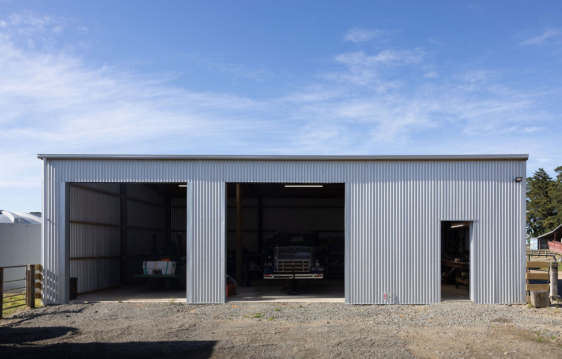 A large white metal garage with a blue sky in the background.