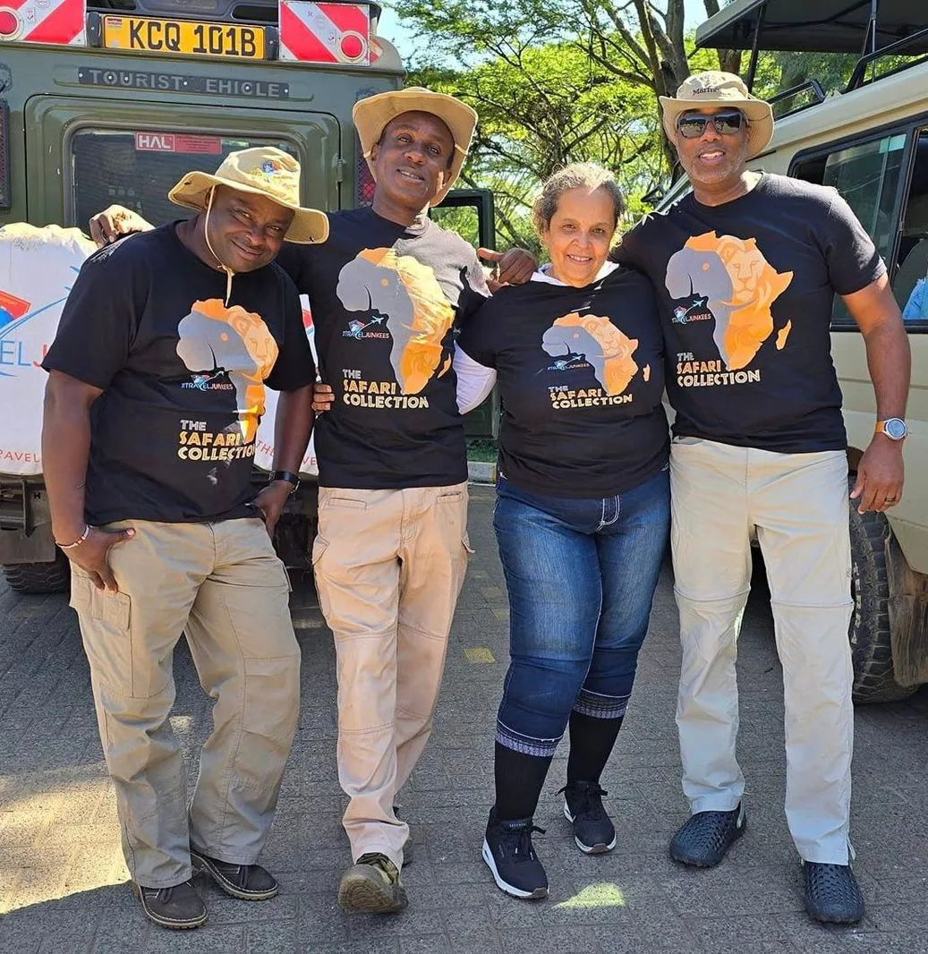 Four people in matching black Africa-themed T-shirts standing outdoors in front of a vehicle.