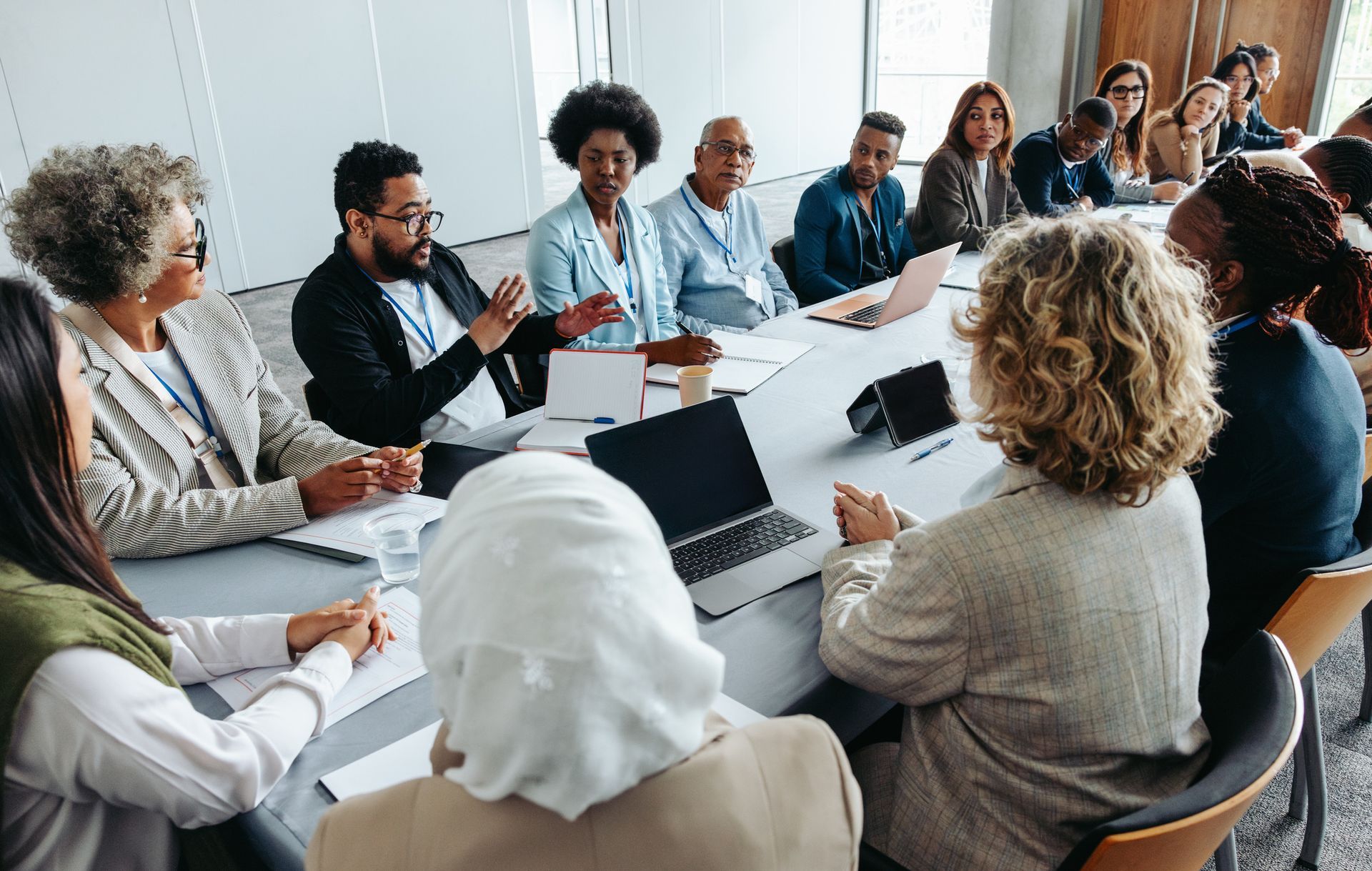 A diverse group of people sitting around a conference table in an office, actively participating in a business meeting.
