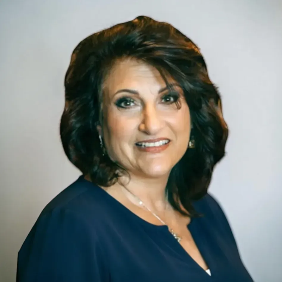 Portrait of a woman with dark hair in a navy top against a light gray background