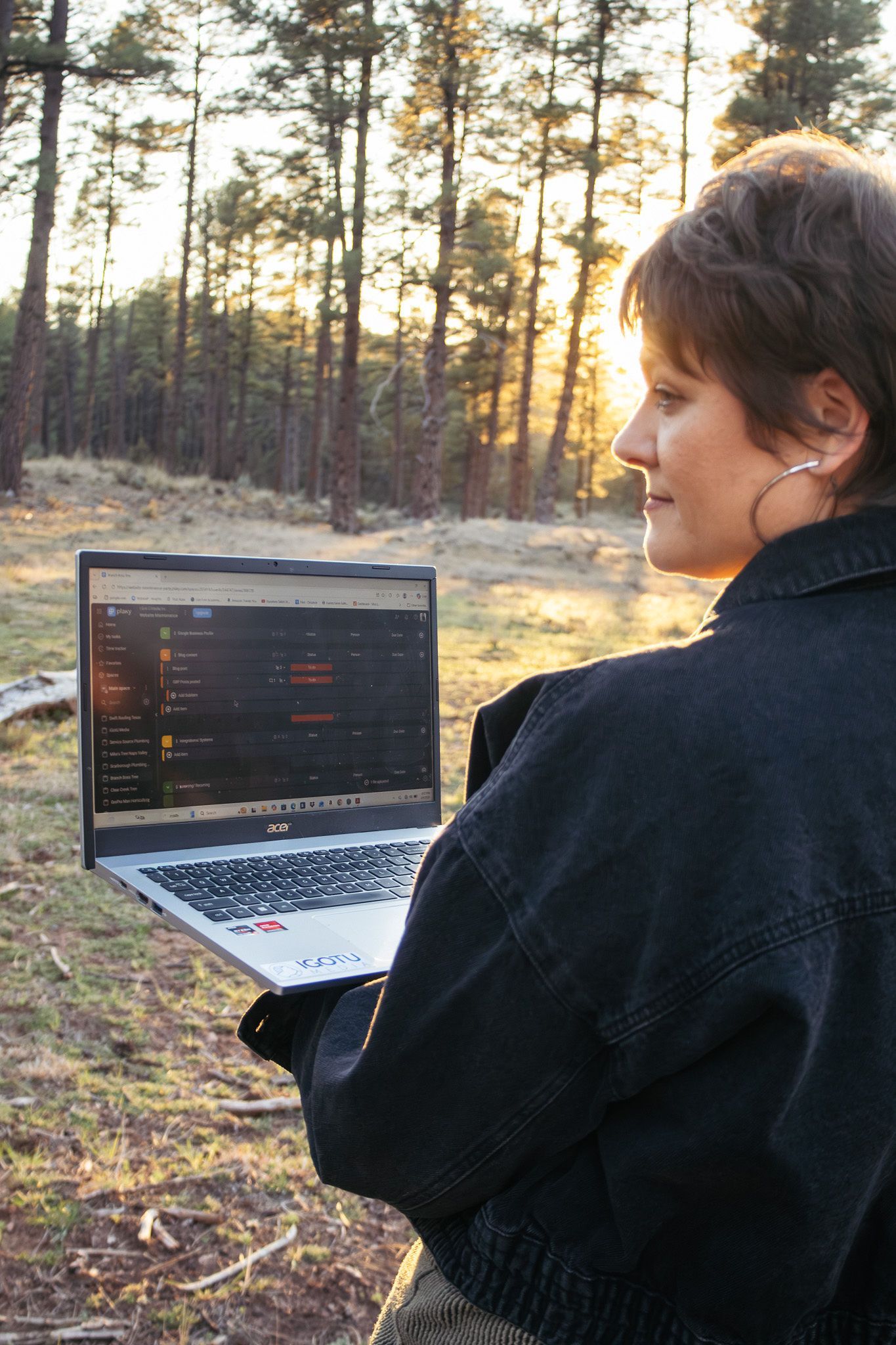 Person using a laptop outdoors in a forest at sunset