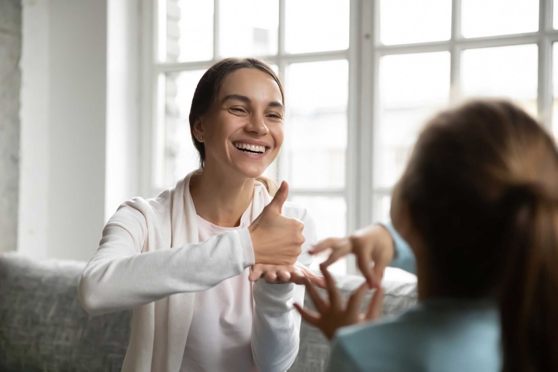Smiling carer using sign language with small child. Smiling carer using sign language with small child.