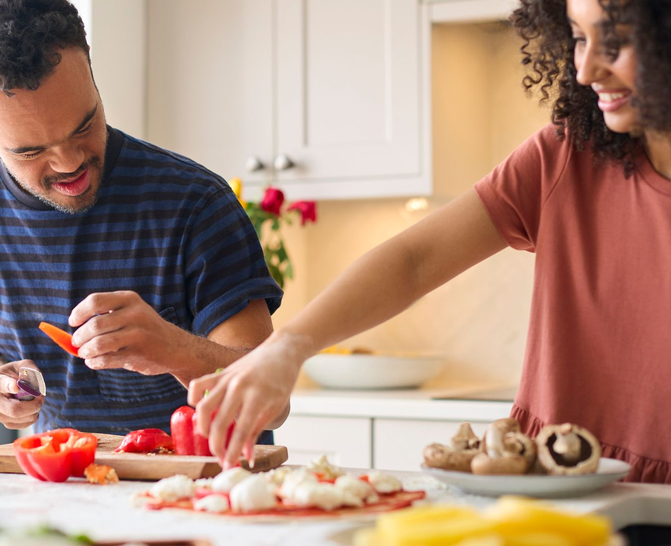 A man and woman prepare together a homemade pizza, inside a kitchen. A man and woman prepare together a homemade pizza, inside a kitchen.