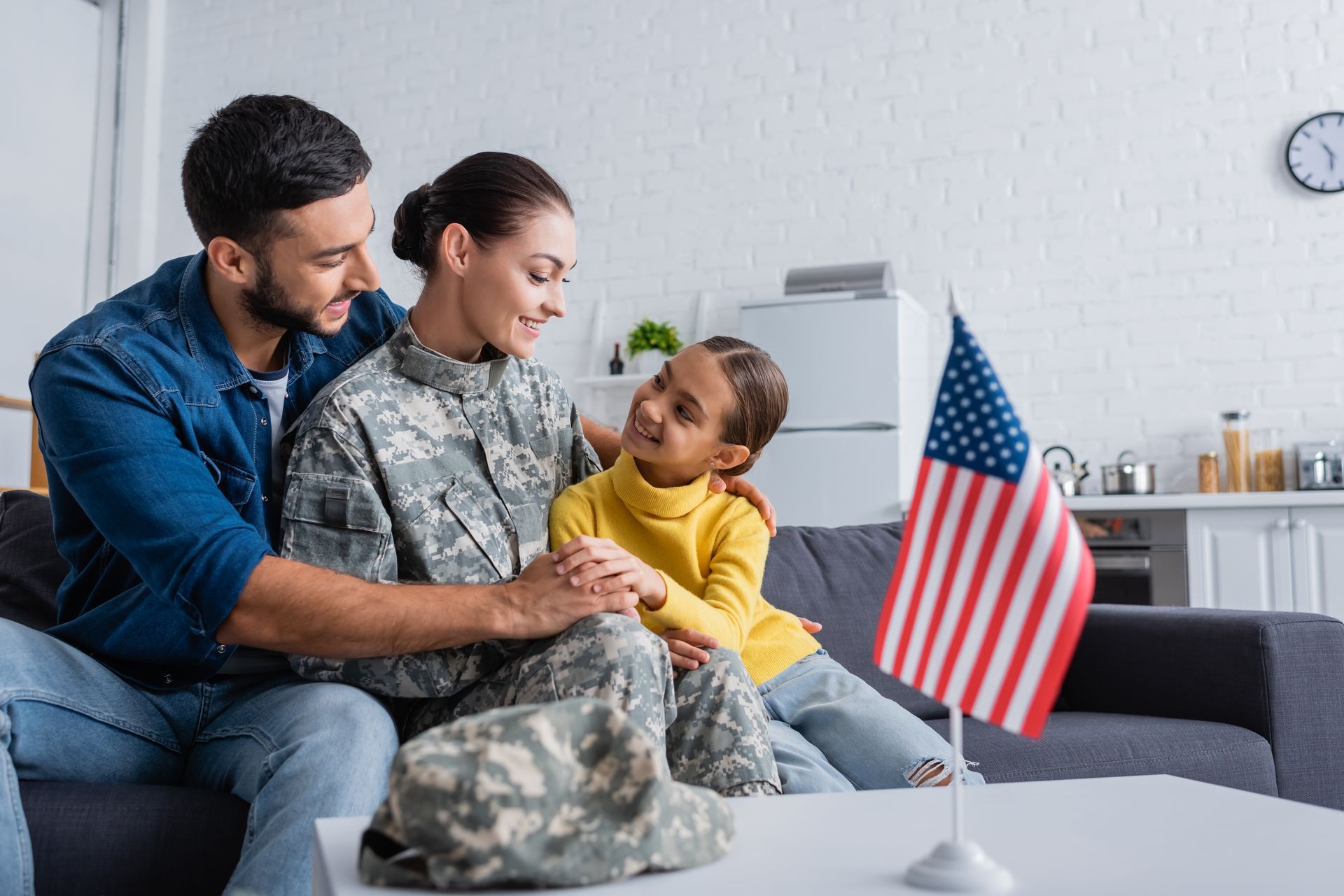 Family sitting on a couch with a child holding a small American flag in a living room