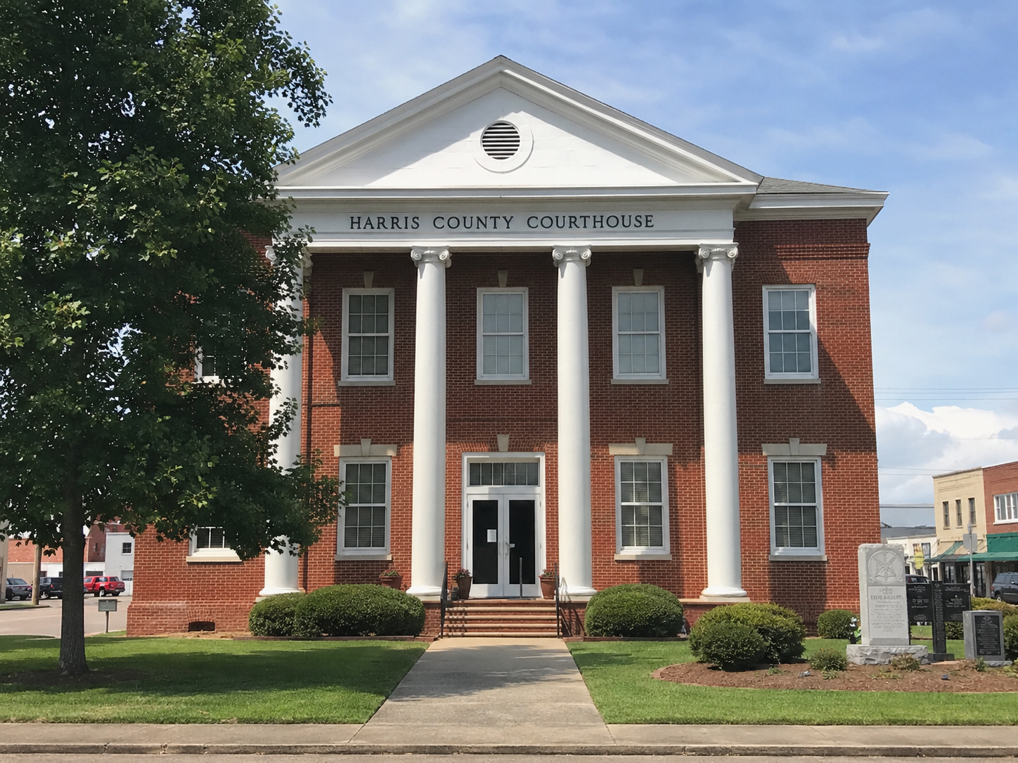 Historic red-brick courthouse with white columns and a pediment, seen from the front.