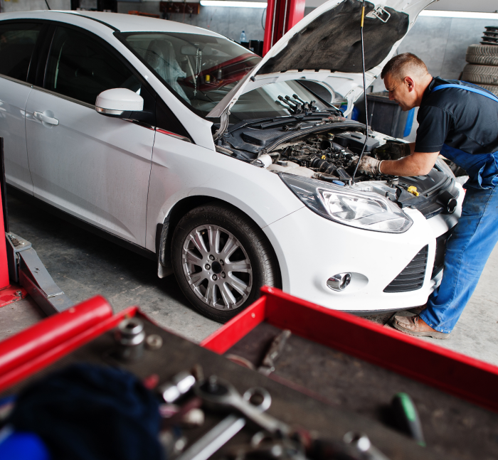 Auto repair shop with several cars on lifts and a mechanic working under a raised hood