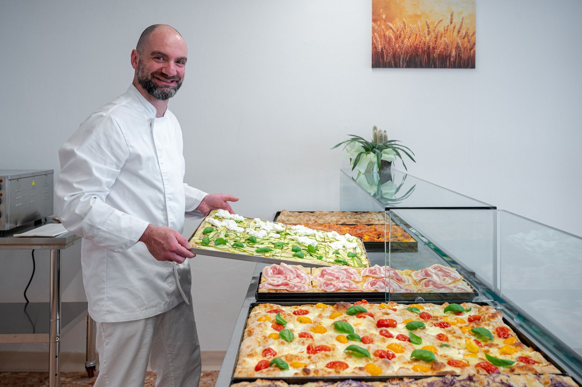 Un uomo serve cibo dai vassoi del buffet in una luminosa mensa, tenendo in mano un vassoio di insalata.