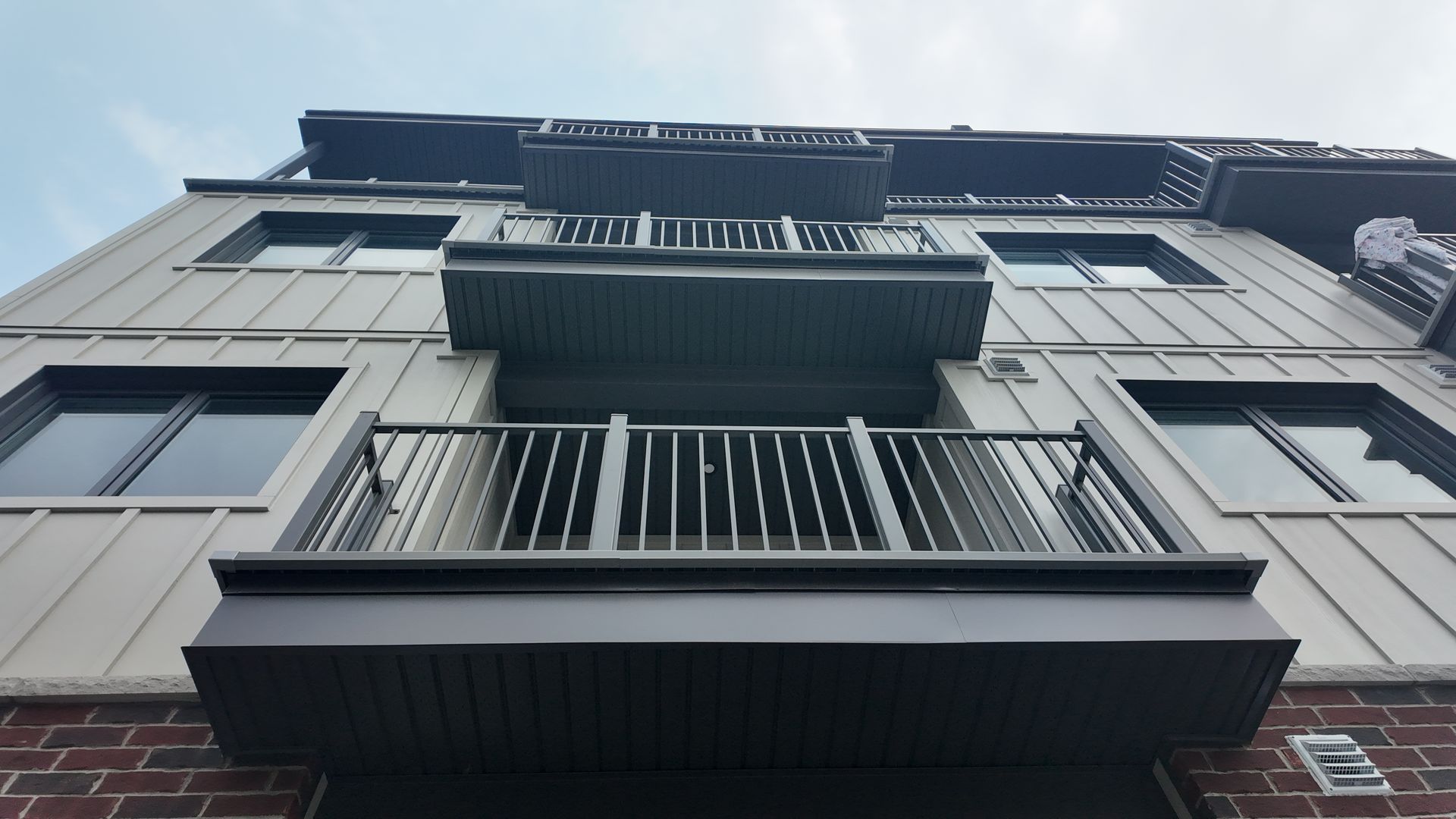 Vue en contre-plongée d’un immeuble d’habitation moderne avec des balcons et un bardage extérieur foncé