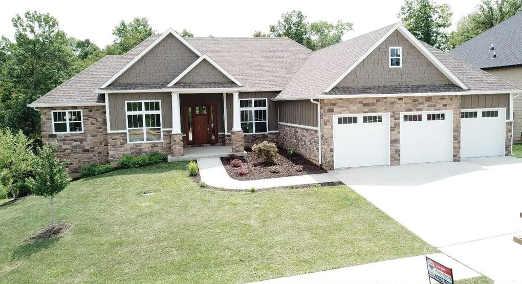 Brick suburban house with front lawn, three-car garage, and a curved walkway