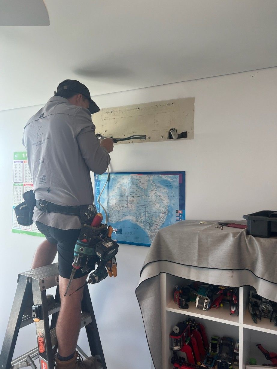 A Man is Standing on a Ladder Working on an Air Conditioner — Kilowatts & Cool Whitsundays In Proserpine, QLD