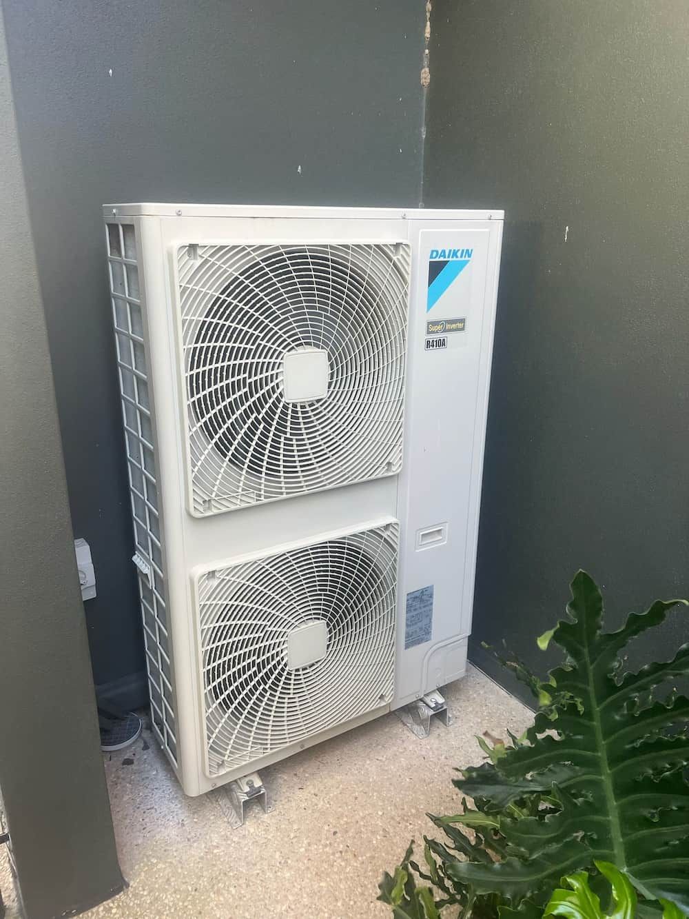 A Large White Air Conditioner is Sitting Outside Next to a Wall — Kilowatts & Cool Whitsundays In Airlie Beach, QLD