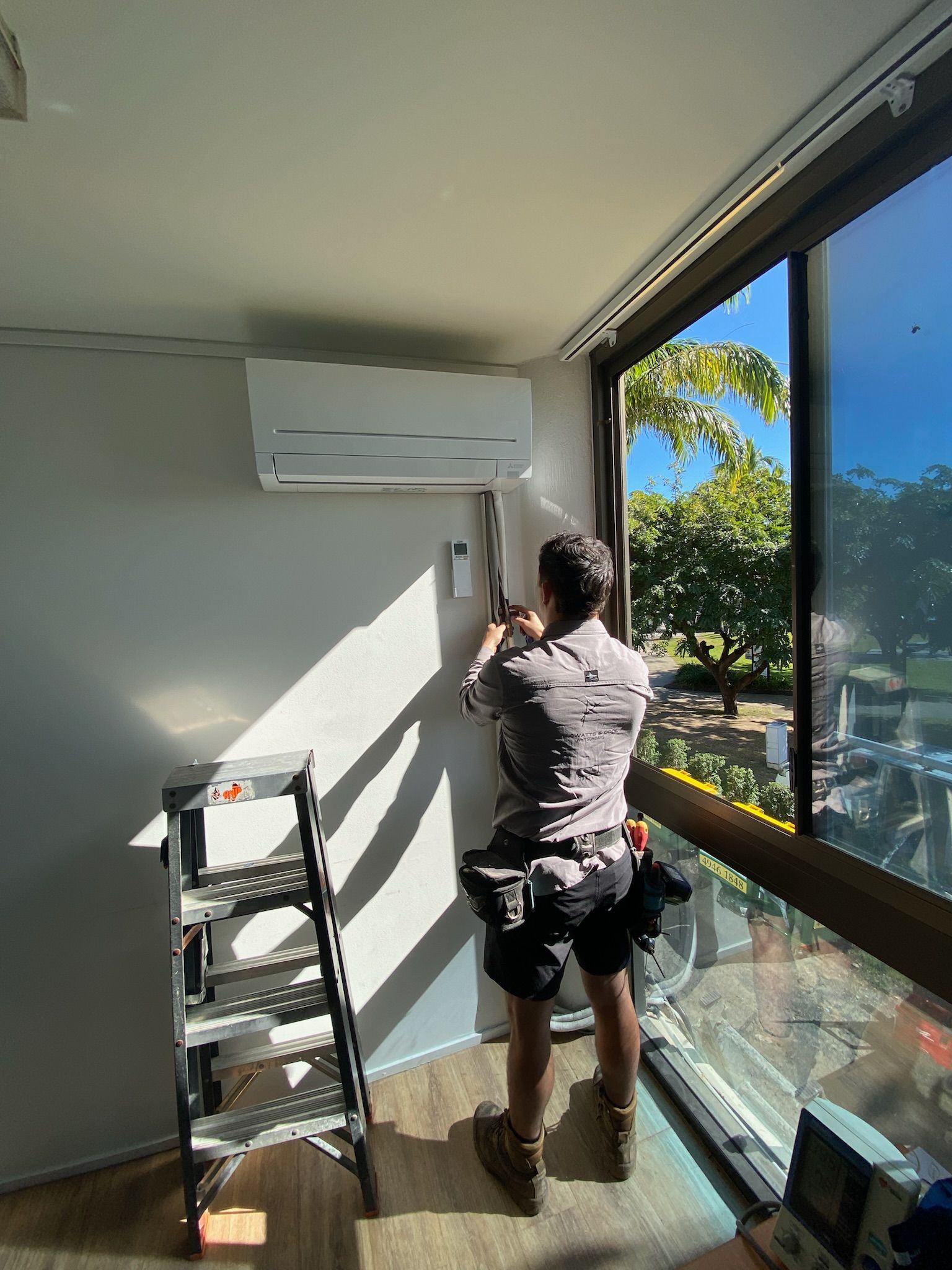 A Man Organising Cable For An Air Conditioning Unit — Kilowatts & Cool Whitsundays In Proserpine, QLD