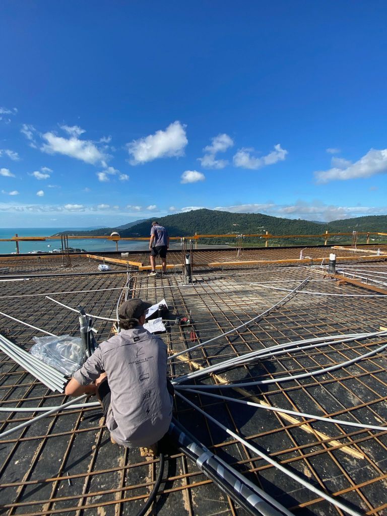 A Group of Construction Workers Are Working on a Roof Overlooking the Ocean — Kilowatts & Cool Whitsundays In Proserpine, QLD