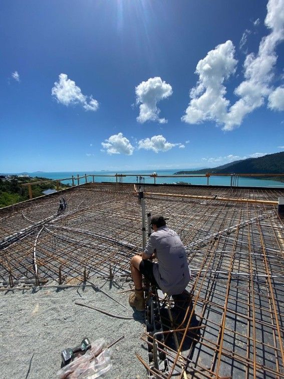A Man is Sitting on the Roof of a Building Overlooking the Ocean — Kilowatts & Cool Whitsundays In Airlie Beach, QLD