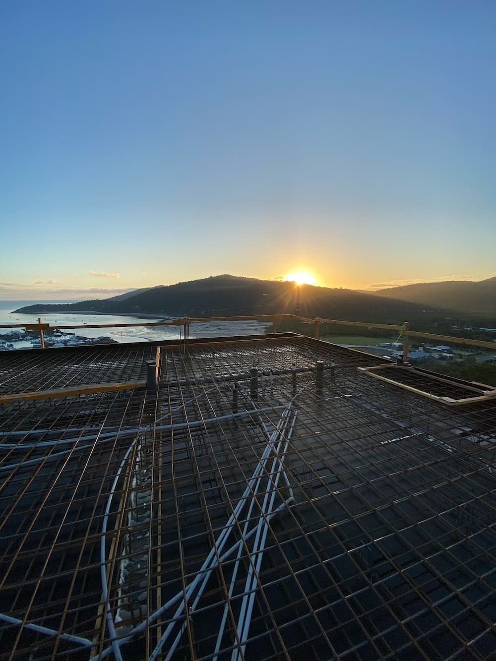 The Sun is Setting Over a Construction Site With a View of the Ocean — Kilowatts & Cool Whitsundays In Airlie Beach, QLD