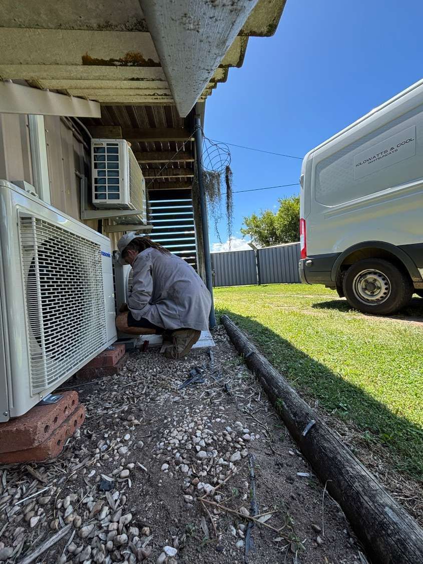 A Man is Working on an Air Conditioner Outside of a House — Kilowatts & Cool Whitsundays In Strathdickie, QLD