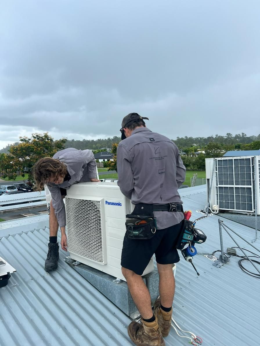 Two Men Are Working on An Air Conditioner on A Roof — Kilowatts & Cool Whitsundays In Proserpine, QLD