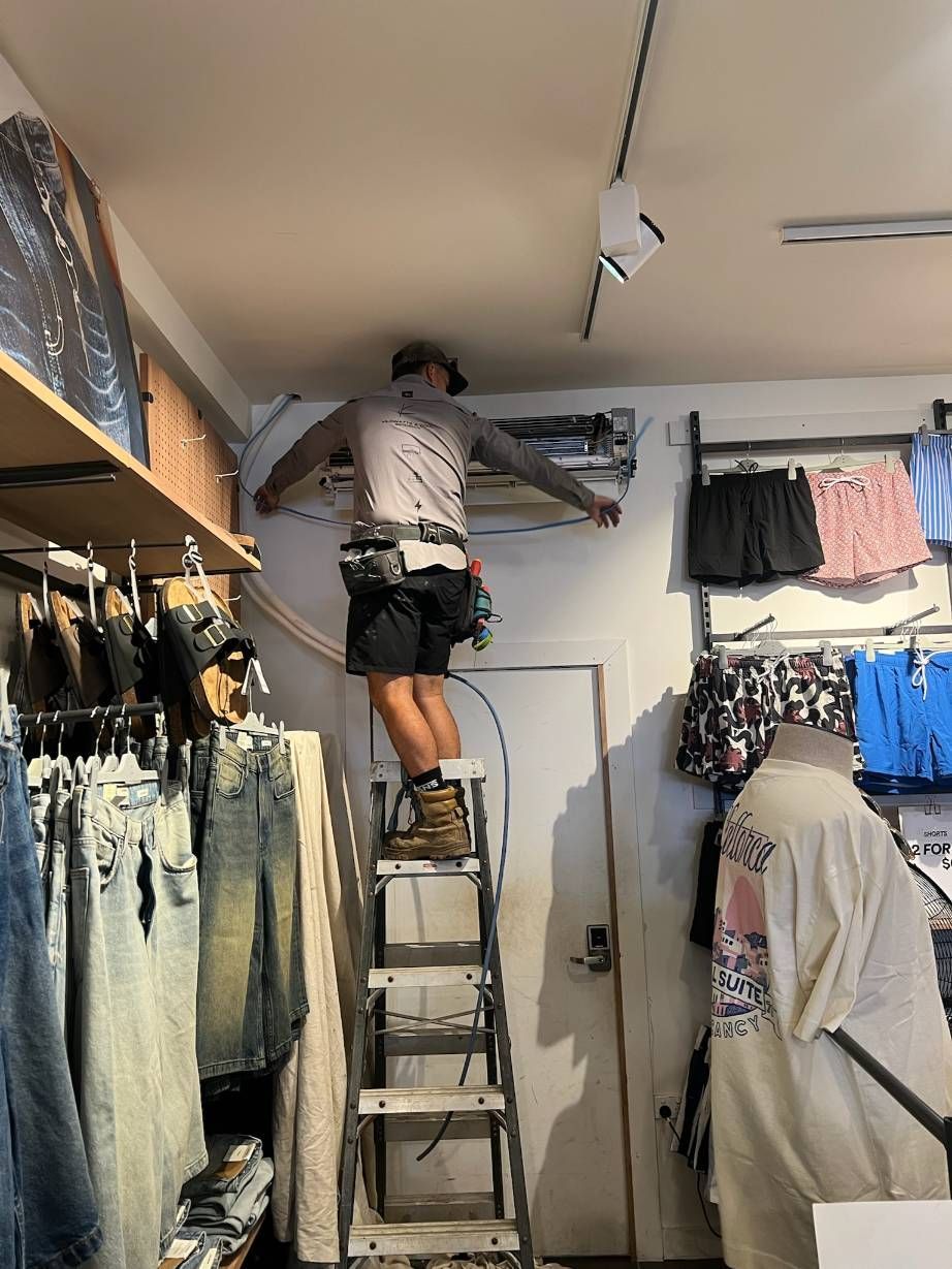 A Man is Standing on a Ladder in a Clothing Store — Kilowatts & Cool Whitsundays In Strathdickie, QLD