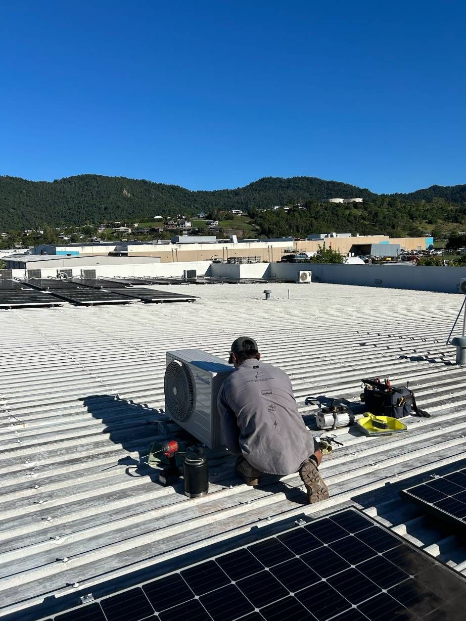 A Man is Working on a Roof With Solar Panels — Kilowatts & Cool Whitsundays In Strathdickie, QLD