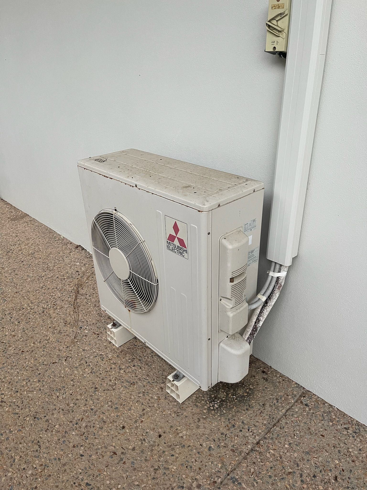 A Air Conditioning Unit Sitting Outside A House — Kilowatts & Cool Whitsundays In Airlie Beach, QLD