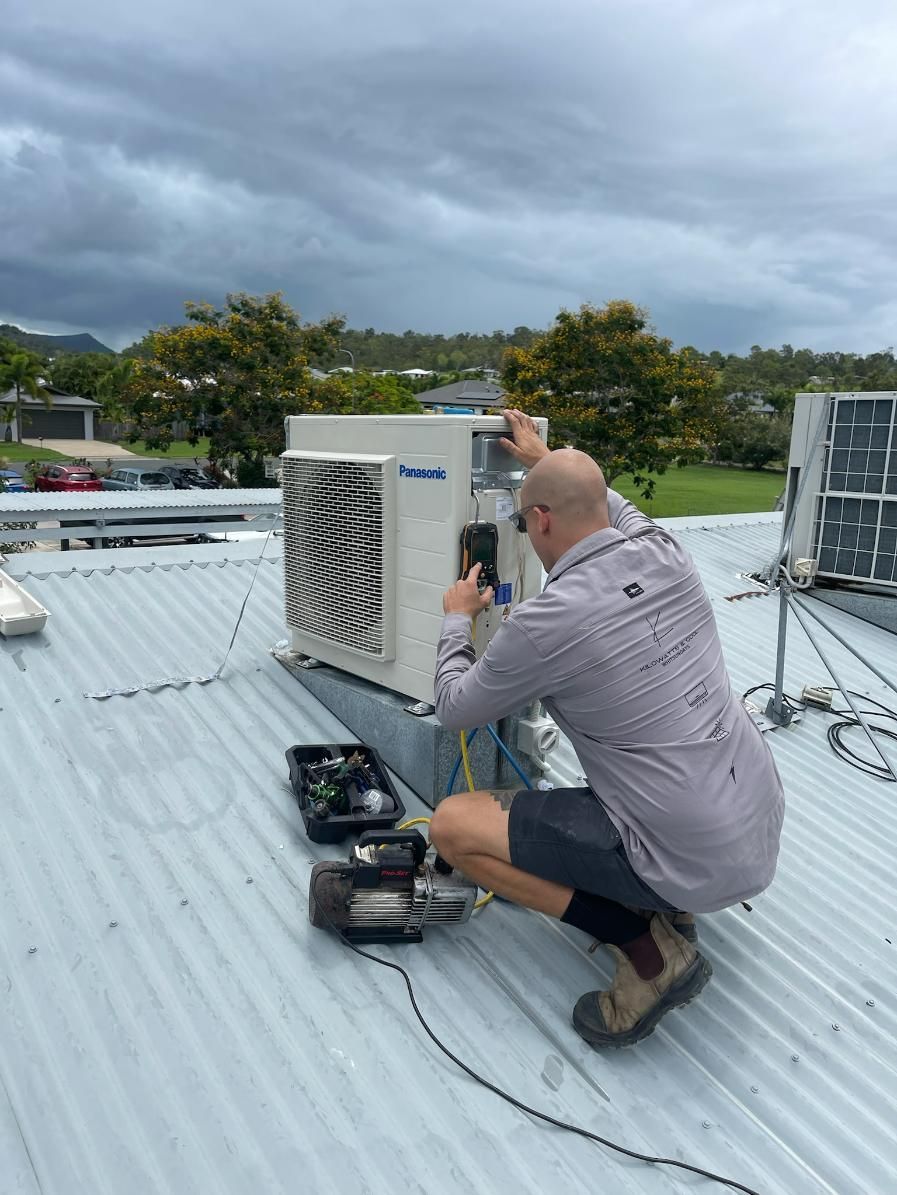 A Man Fixing An Air Conditioner on A Roof — Kilowatts & Cool Whitsundays In Cannonvale, QLD