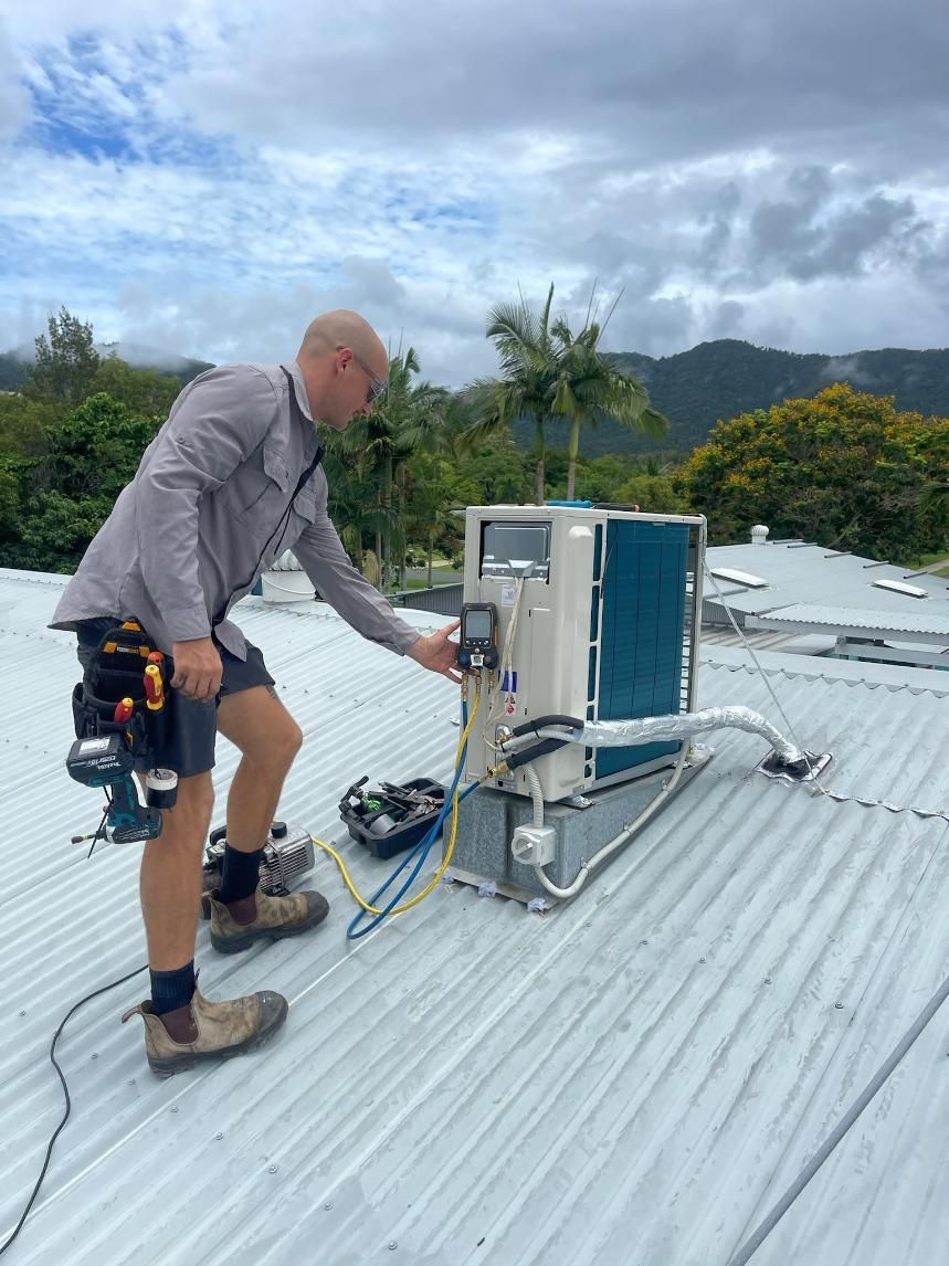 A Man Is Working on An Air Conditioner on The Roof of A Building — Kilowatts & Cool Whitsundays In Strathdickie, QLD
