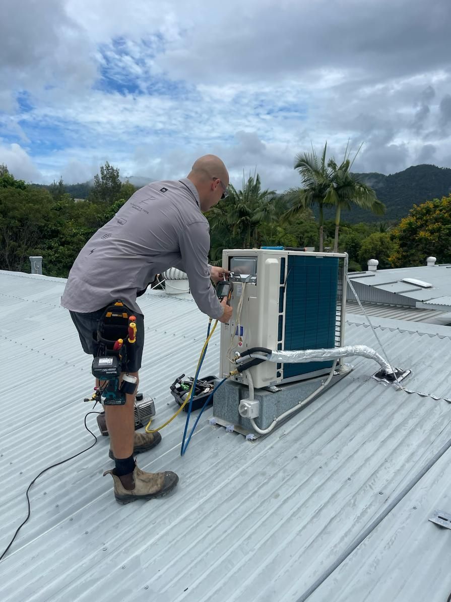 A Man Is Fixing An Air Conditioner on A Roof — Kilowatts & Cool Whitsundays In Strathdickie, QLD