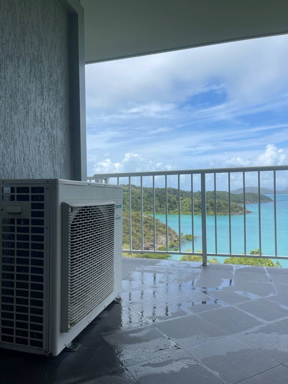 An Air Conditioner is Sitting on a Balcony Overlooking the Ocean — Kilowatts & Cool Whitsundays In Cannonvale, QLD