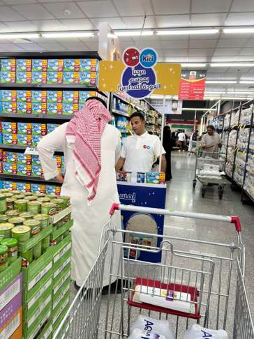 A man standing next to a cart in a grocery store