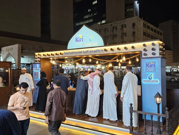 A group of people standing in front of a kiosk that says ' kin ' on it