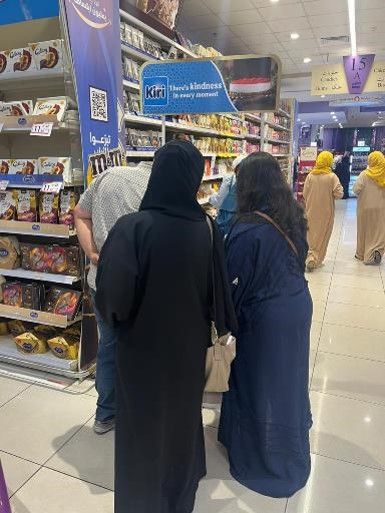 A group of people are standing in a store looking at food.