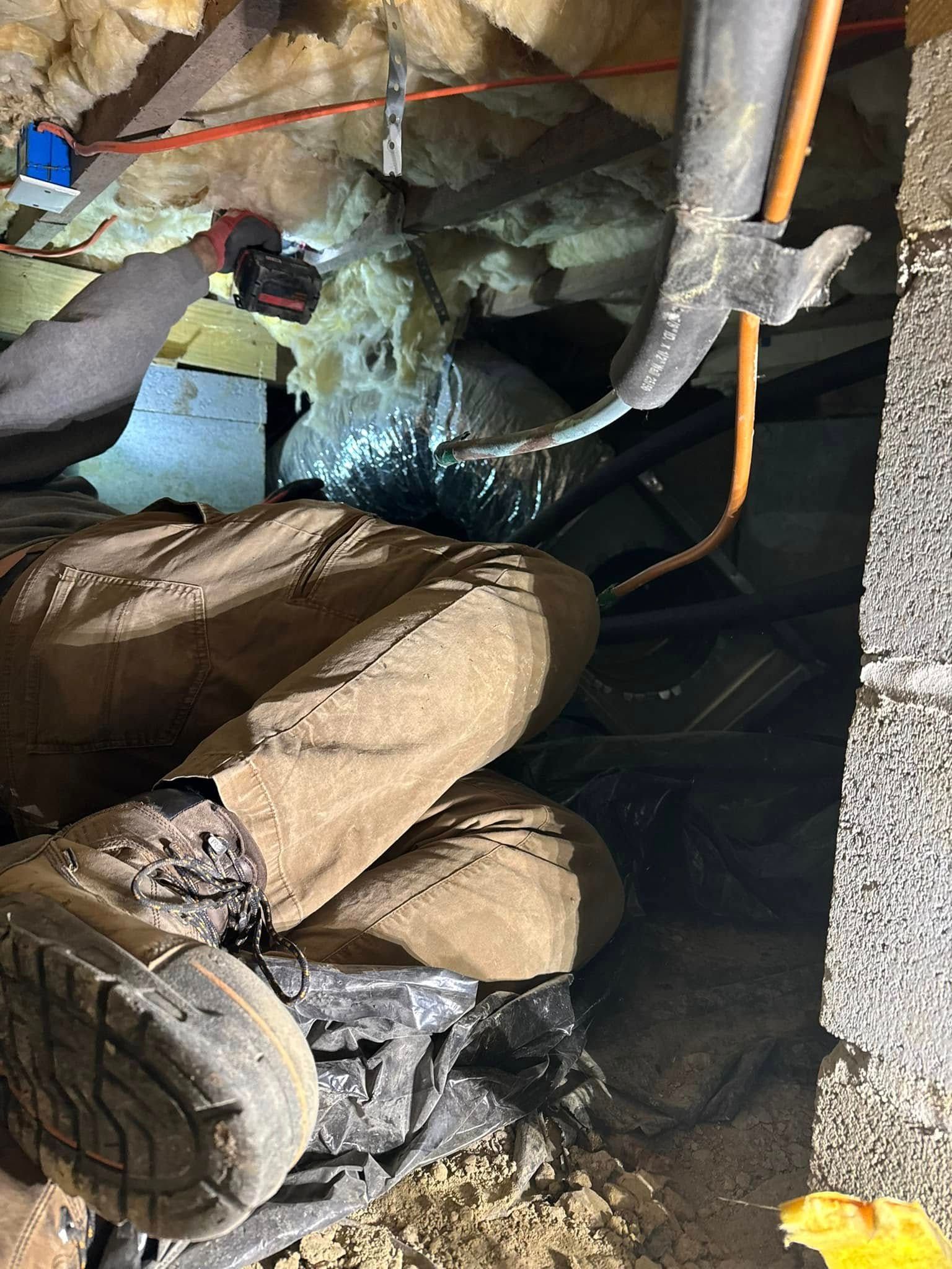 A person is kneeling down in an attic with a pair of boots on.