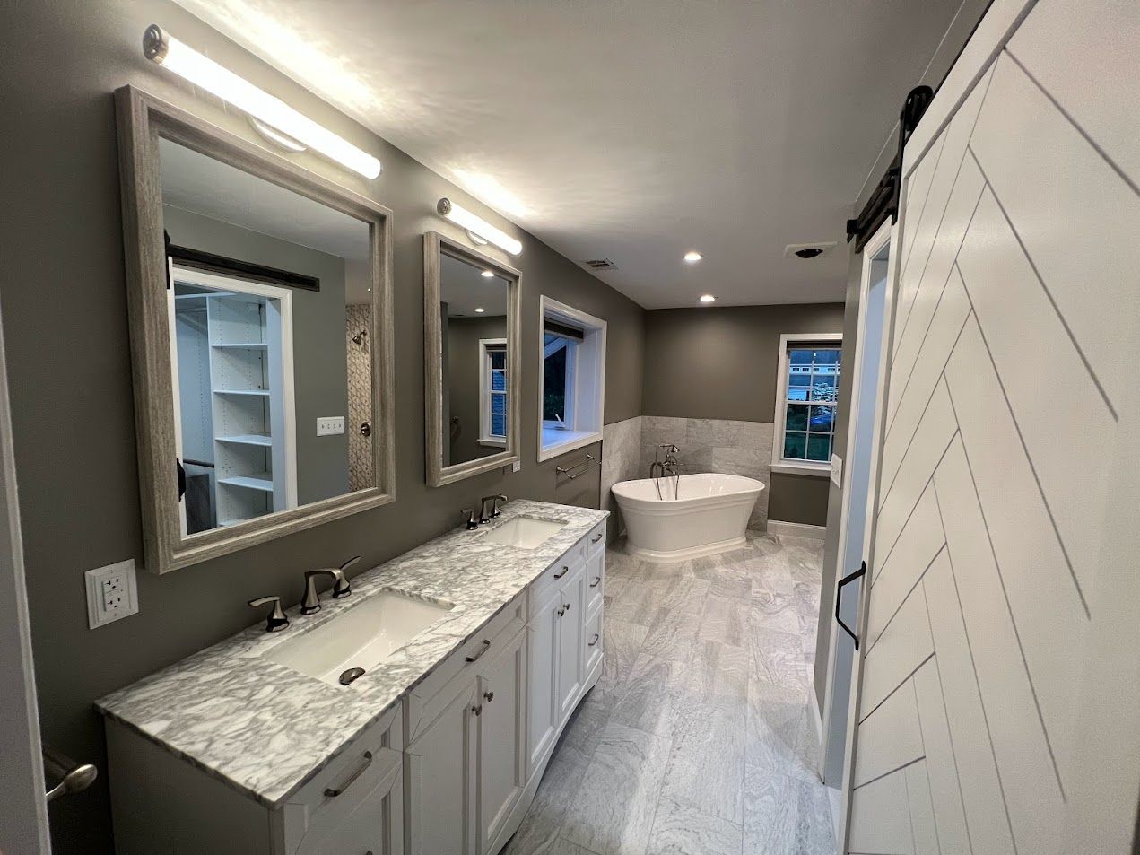 A bathroom with two sinks , two mirrors and a bathtub.