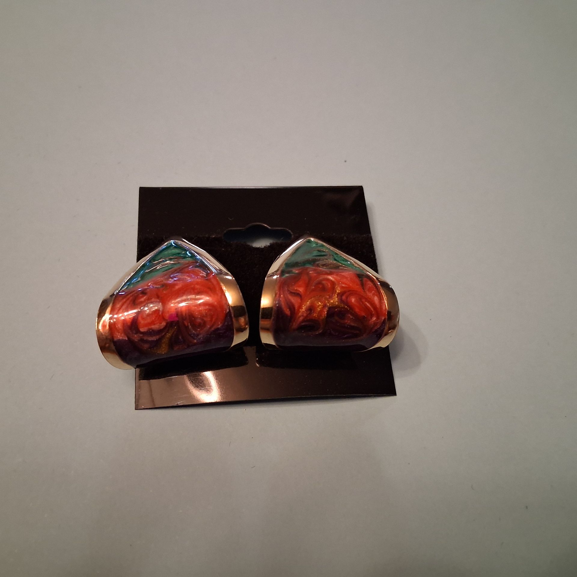 Red and silver metallic earrings on a black display card.