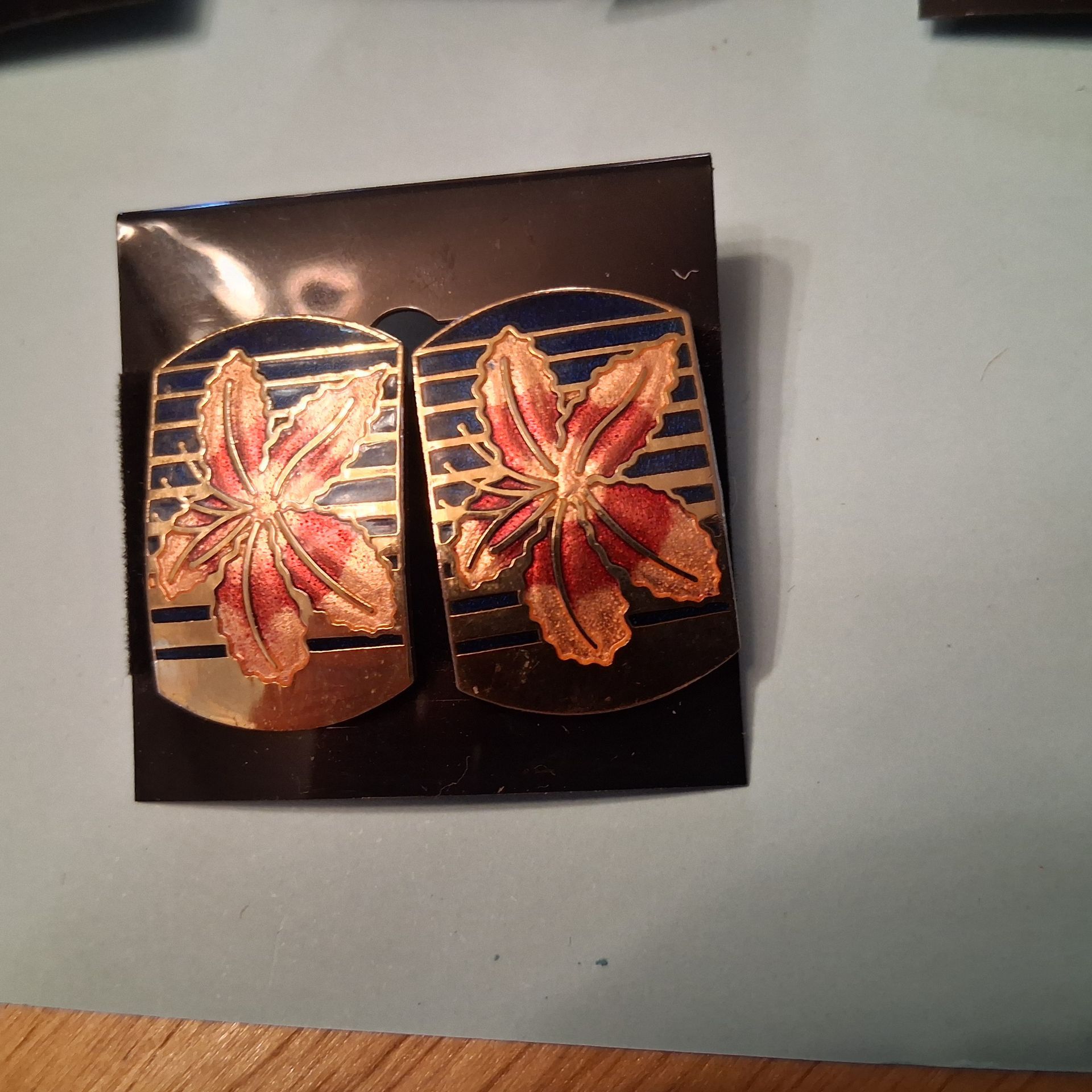 Two decorative earrings with red butterflies on a dark backing card