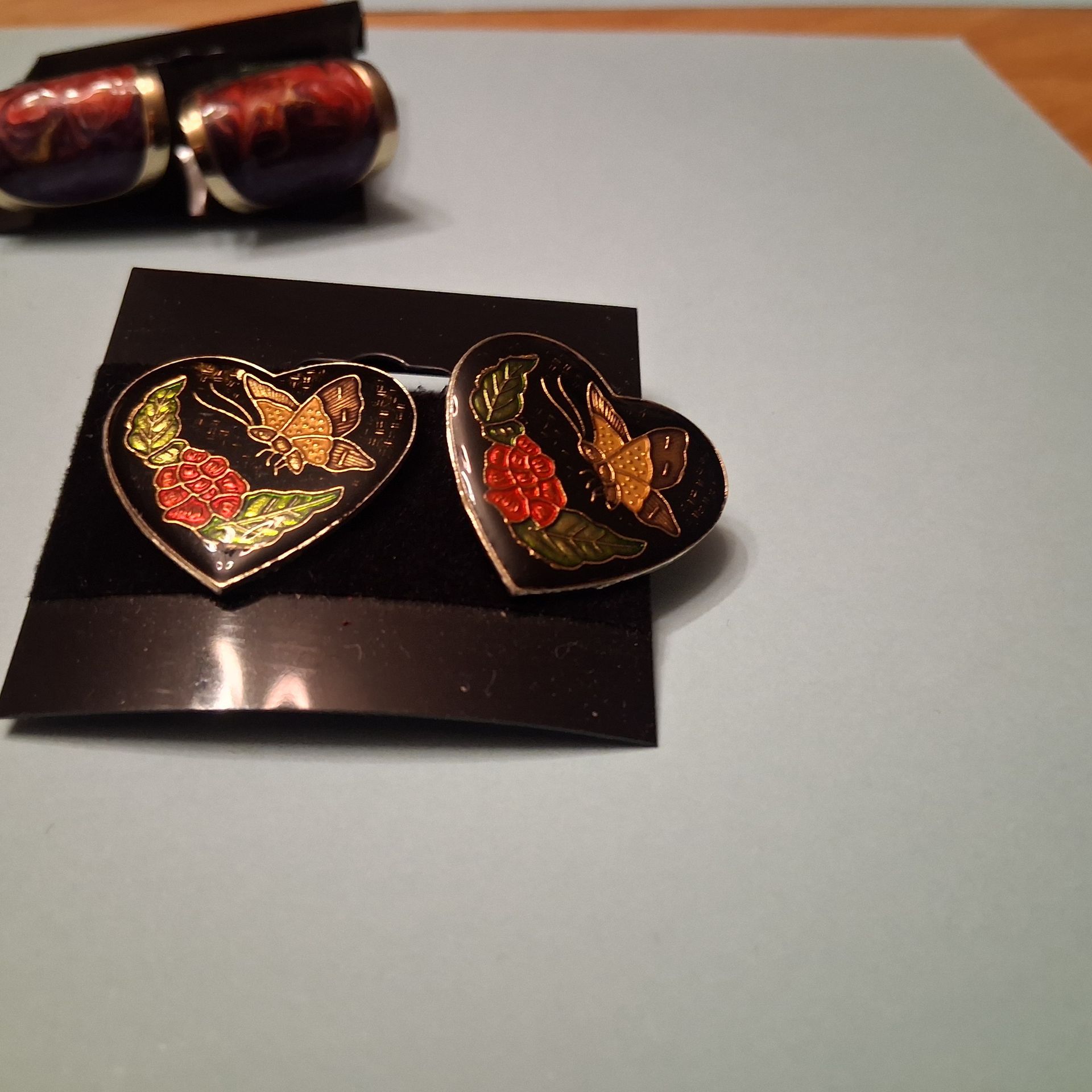 Red and silver metallic earrings on a black display card.