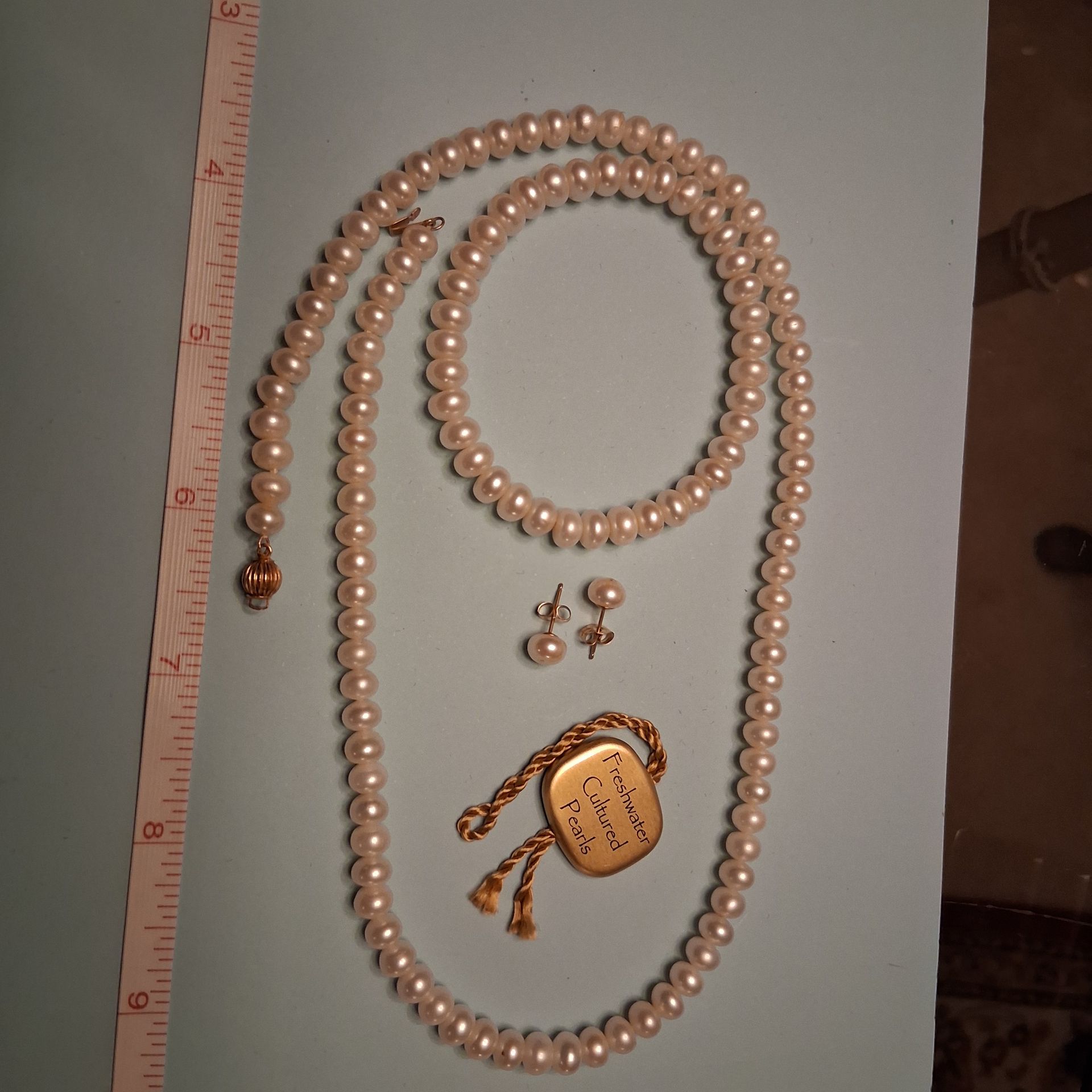 Pearl necklace and matching earrings in a red jewelry box with a gold seal and clasp
