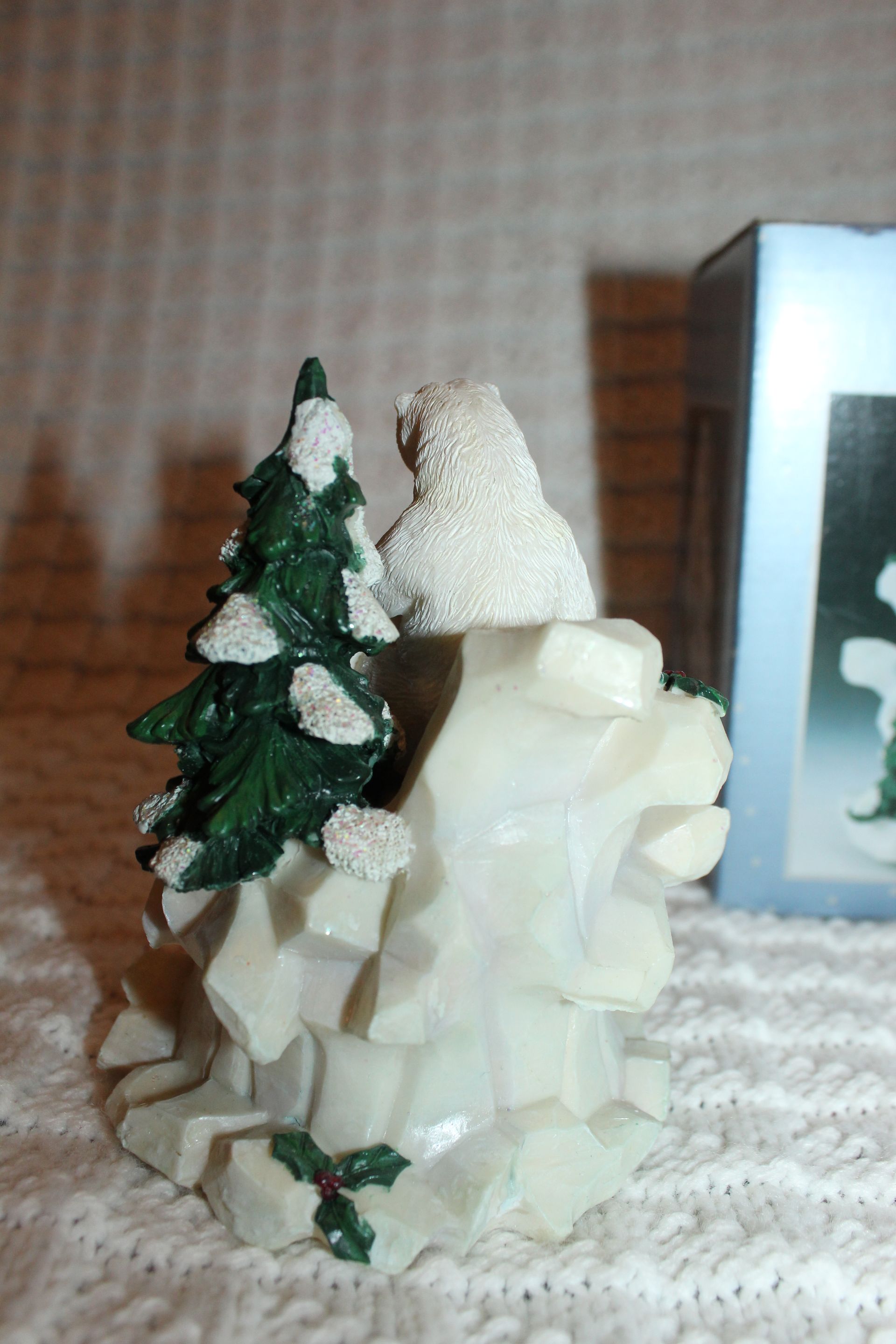 Polar bear figurines on a snowy rock with evergreen trees and a small cave opening