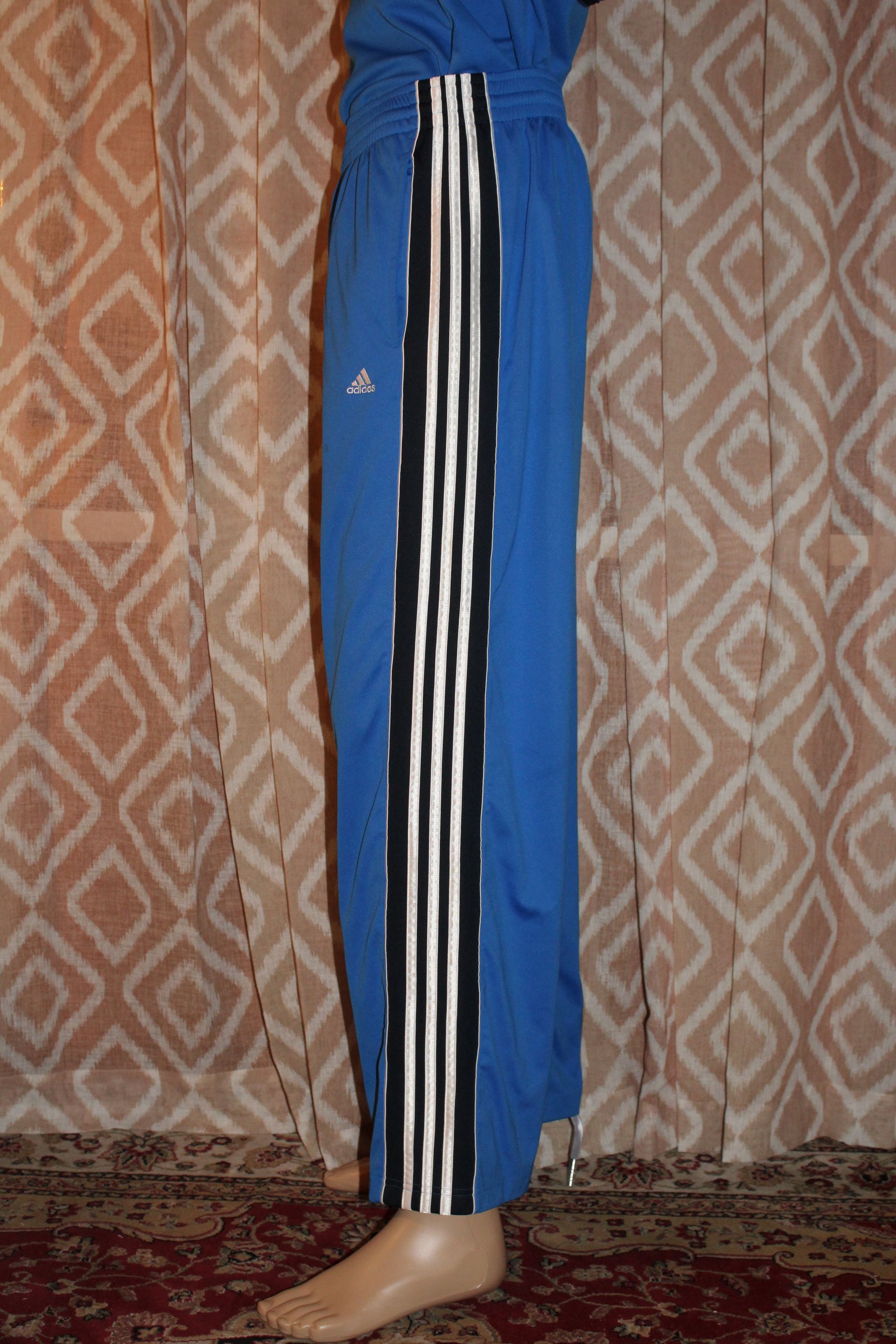 Person in bright blue pants standing indoors against a patterned wall.