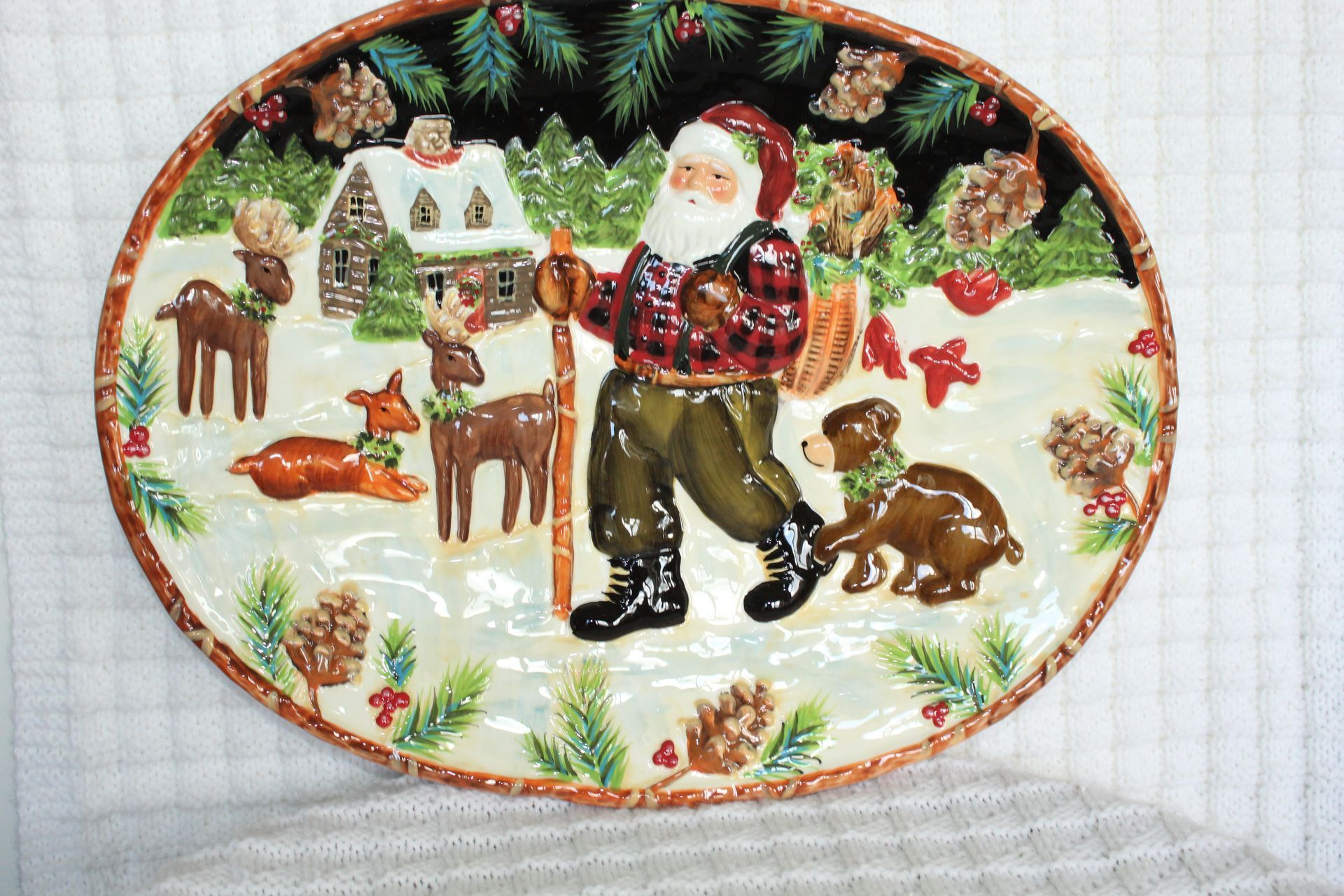Santa with reindeer and a dog in a snowy Christmas scene on an oval plate
