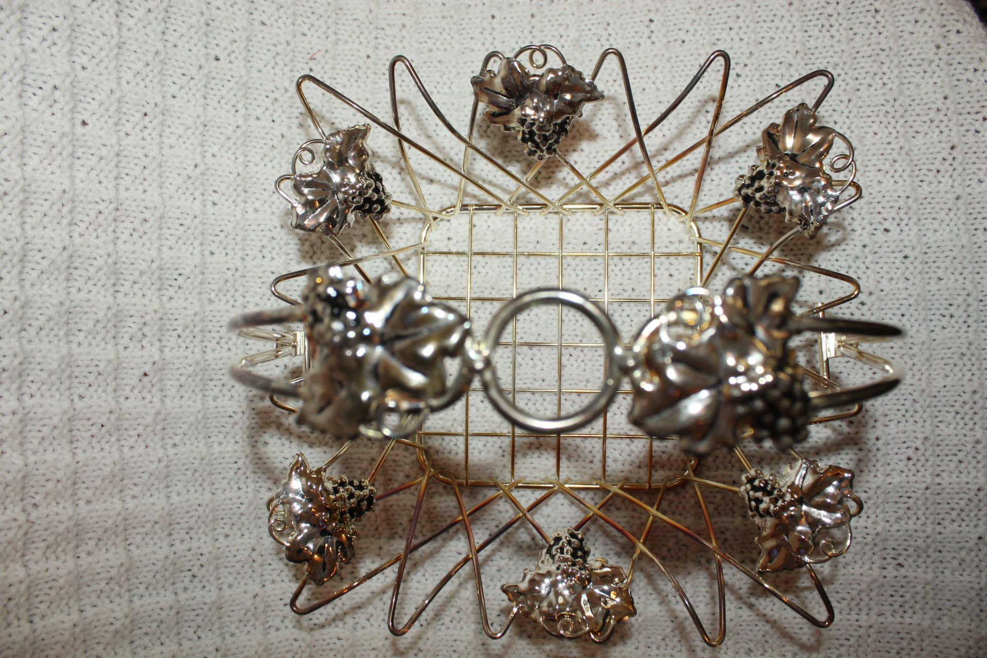 Gold wire basket with floral decorations and a curved handle on a beige background