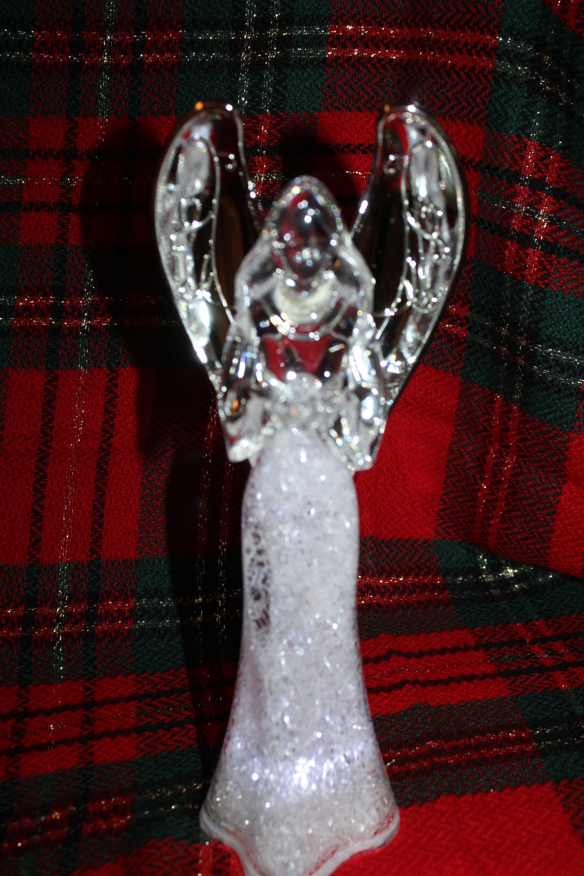 Glittery angel figurine with clear wings on a red plaid background