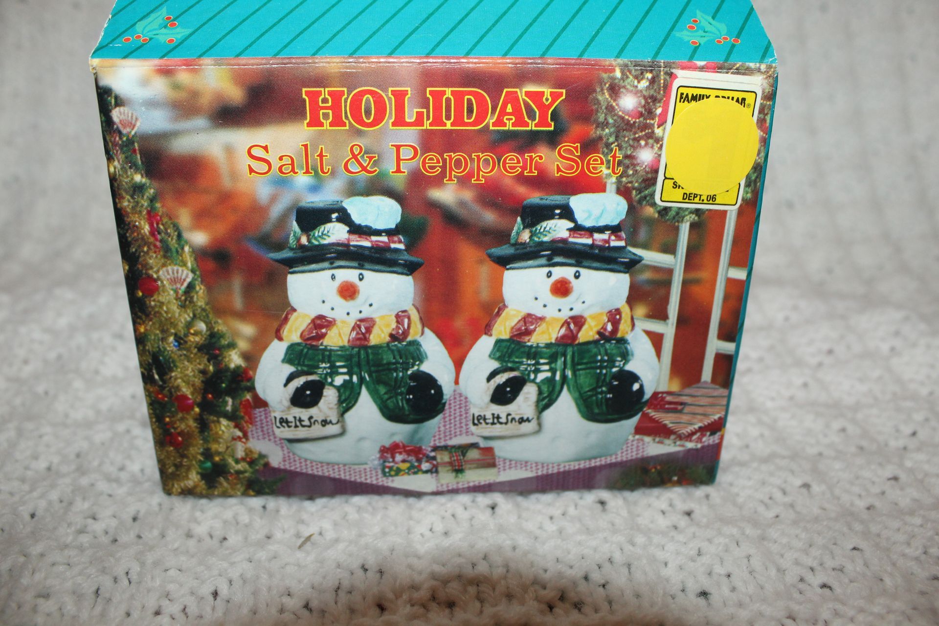 Two small snowman figurines with black hats, colorful scarves, and green mittens on a white blanket
