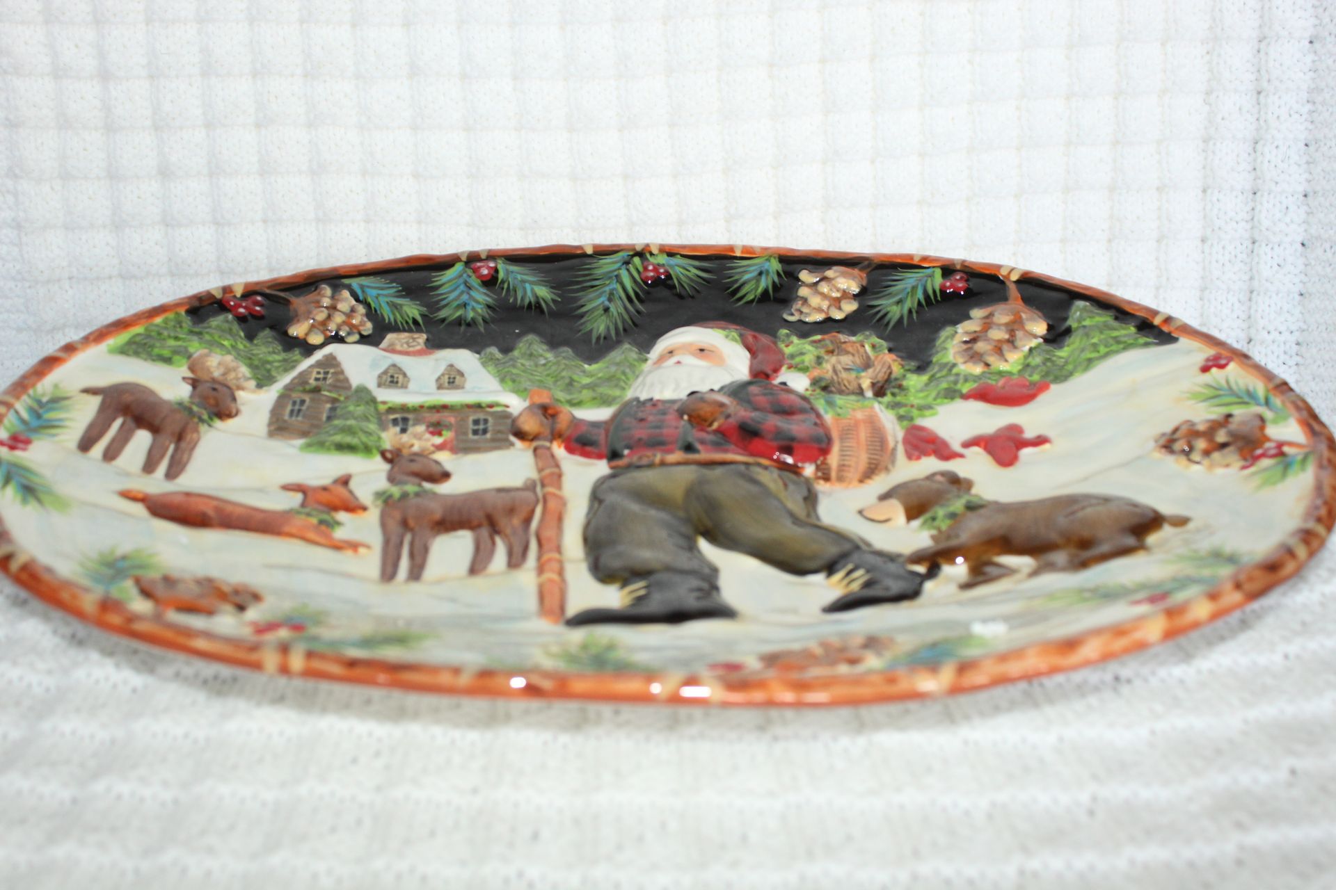 Santa with reindeer and a dog in a snowy Christmas scene on an oval plate