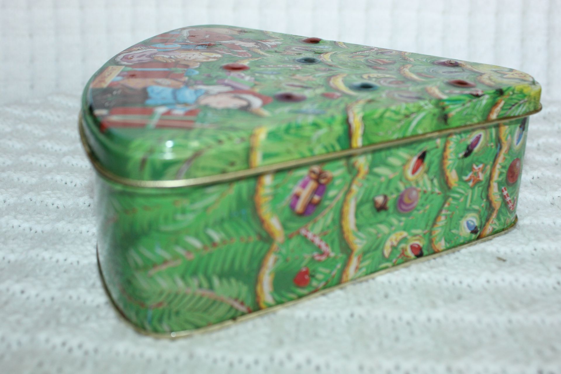 Christmas tree-shaped tin with colorful holiday scene and people decorating it