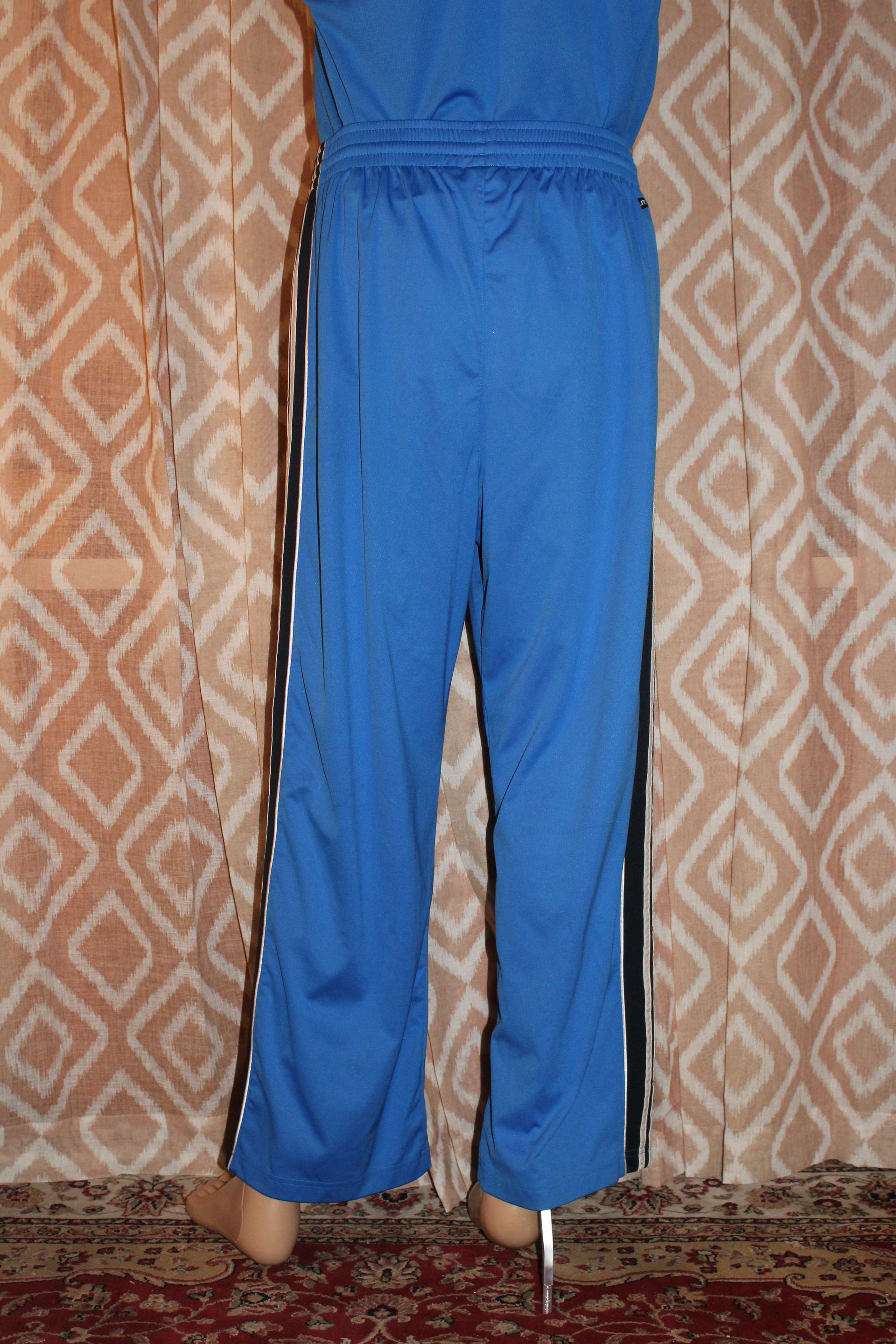 Person in bright blue pants standing indoors against a patterned wall.